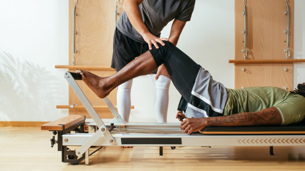 Instructor guiding a diverse group of students in a Reformer Pilates class