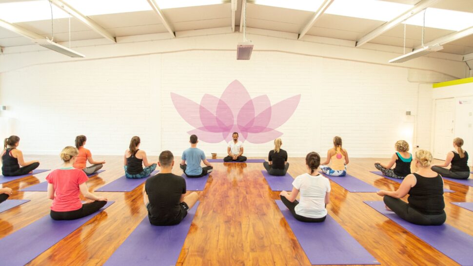 A group of students practising yoga in a bright Cork studio, guided by a teacher, representing unity and community connection.