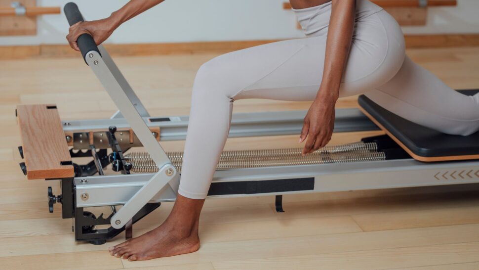 Close-up of legs pushing on reformer machine showing calorie burn and resistance training